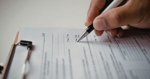 Operatore compila il formulario rifiuti in formato digitale su tablet nell'area di carico di un'azienda
