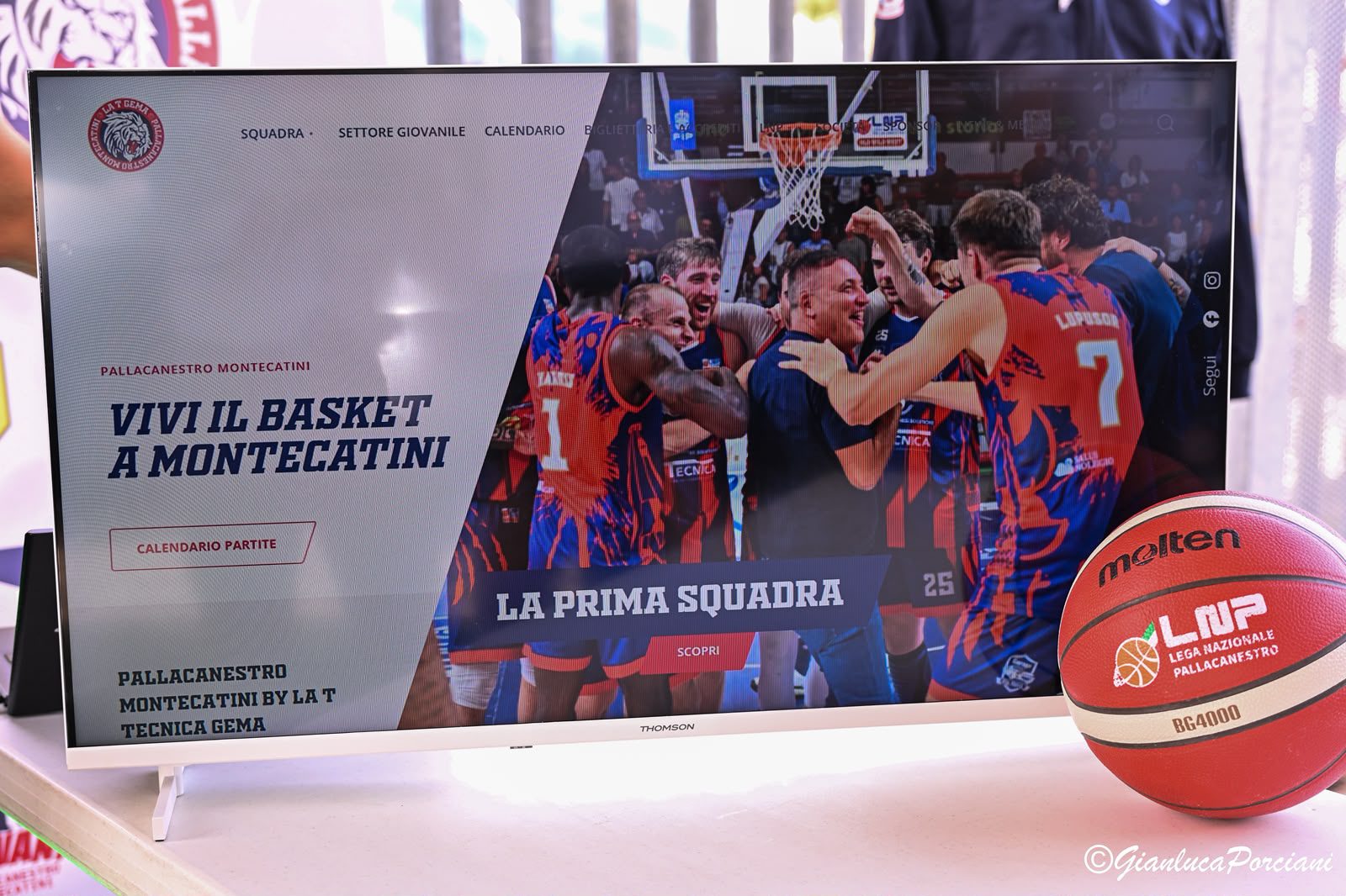 La home del nuovo sito di Pallacanestro Montecatini proiettata su uno schermo, con il titolo Vivi il basket a Montecatini e un pallone accanto